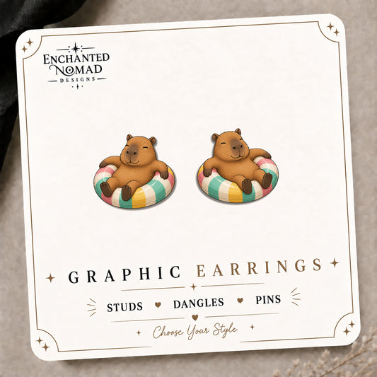 Capybara Pool Float Stud Earrings on the tilted Enchanted Nomad Designs card