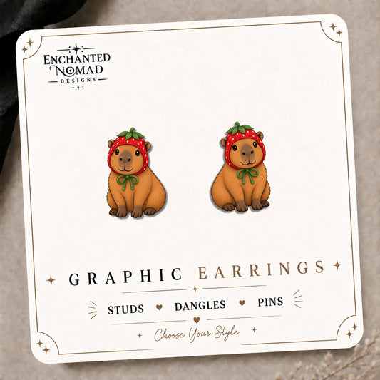 Capybara Strawberry Hat Stud Earrings on the tilted Enchanted Nomad Designs card