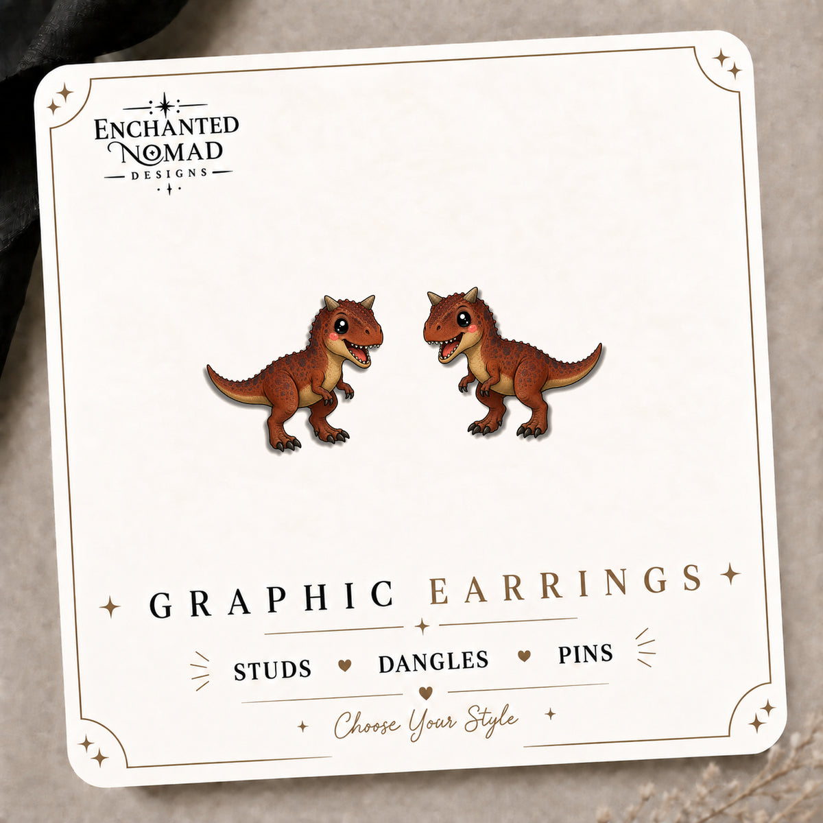 Carnotaurus Stud Earrings on the tilted Enchanted Nomad Designs card