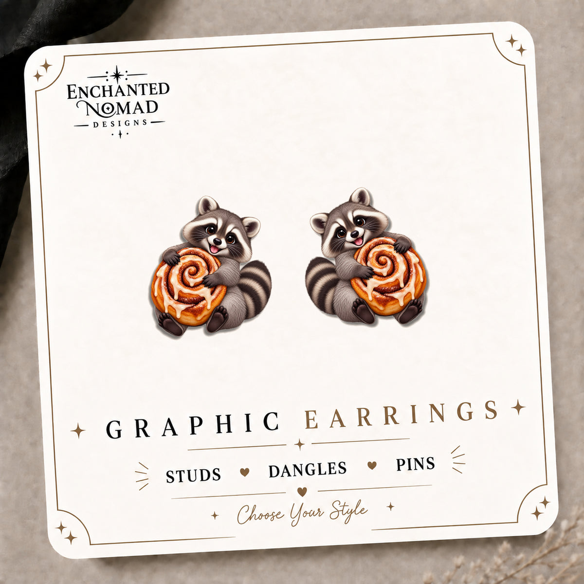 Raccoon Cinnamon Roll Stud Earrings on the tilted Enchanted Nomad Designs card